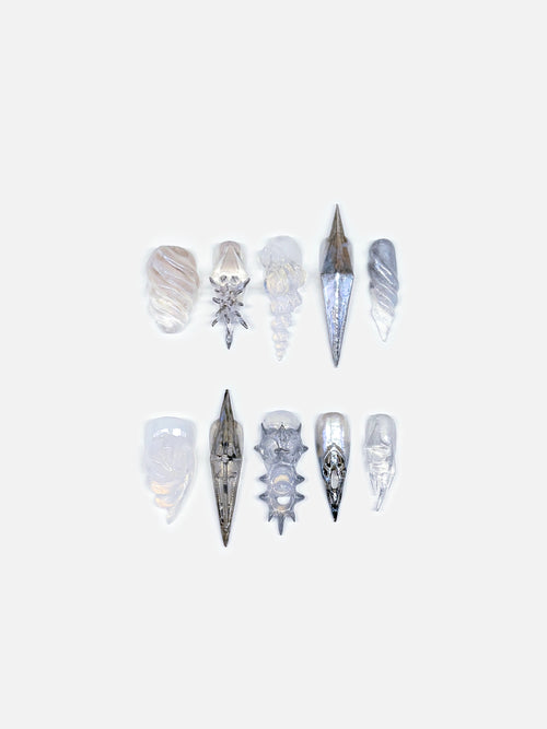Close-up of silver sculptural 3D shell nails, metallic gradients. Each form feels like ocean armor reborn, a poetic fusion of flower nail art and conceptual design. The texture and depth capture the interplay between organic evolution and futuristic craftsmanship, presenting wearable art that transcends ordinary beauty.